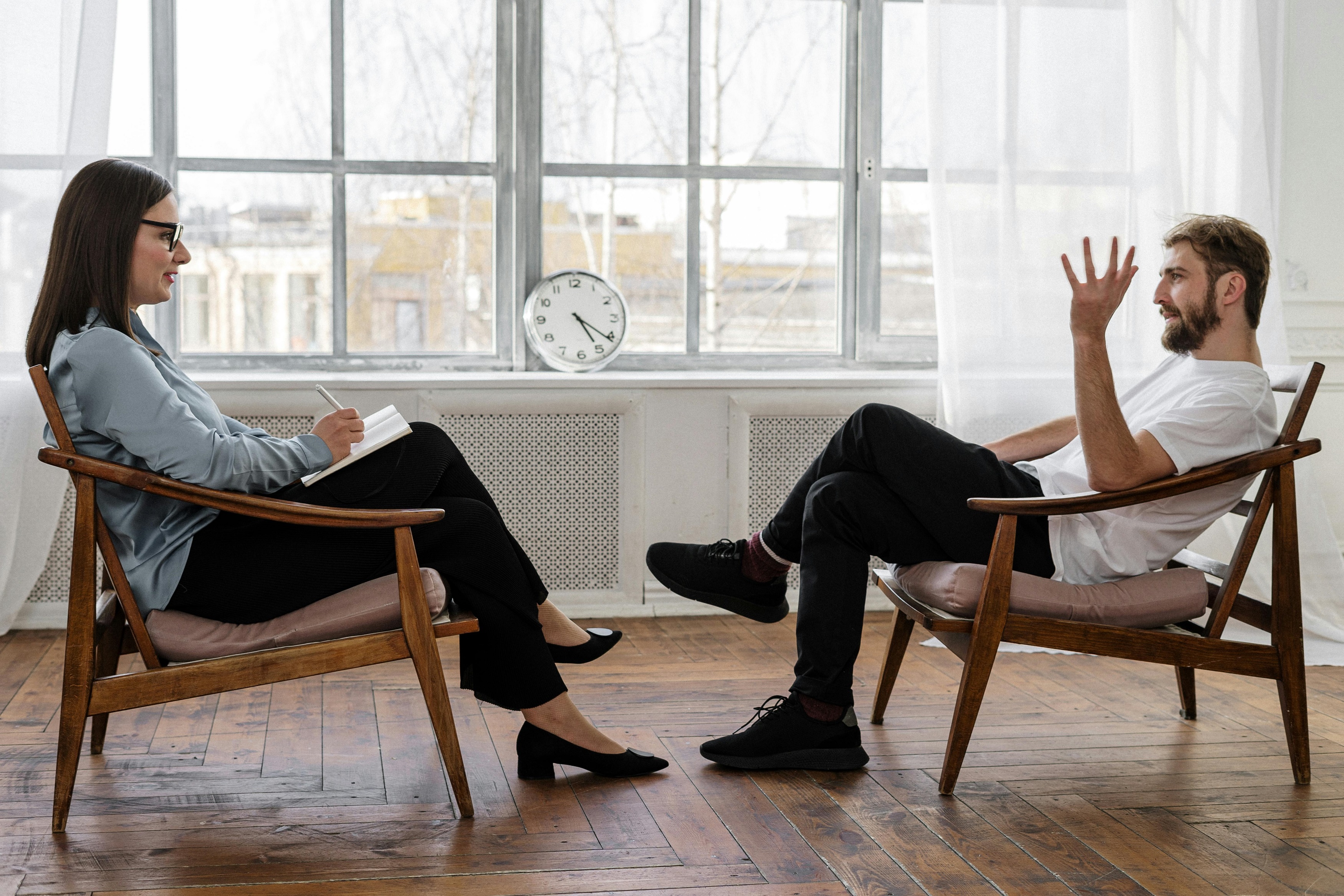Two people sitting and facing each other in a counselling session.